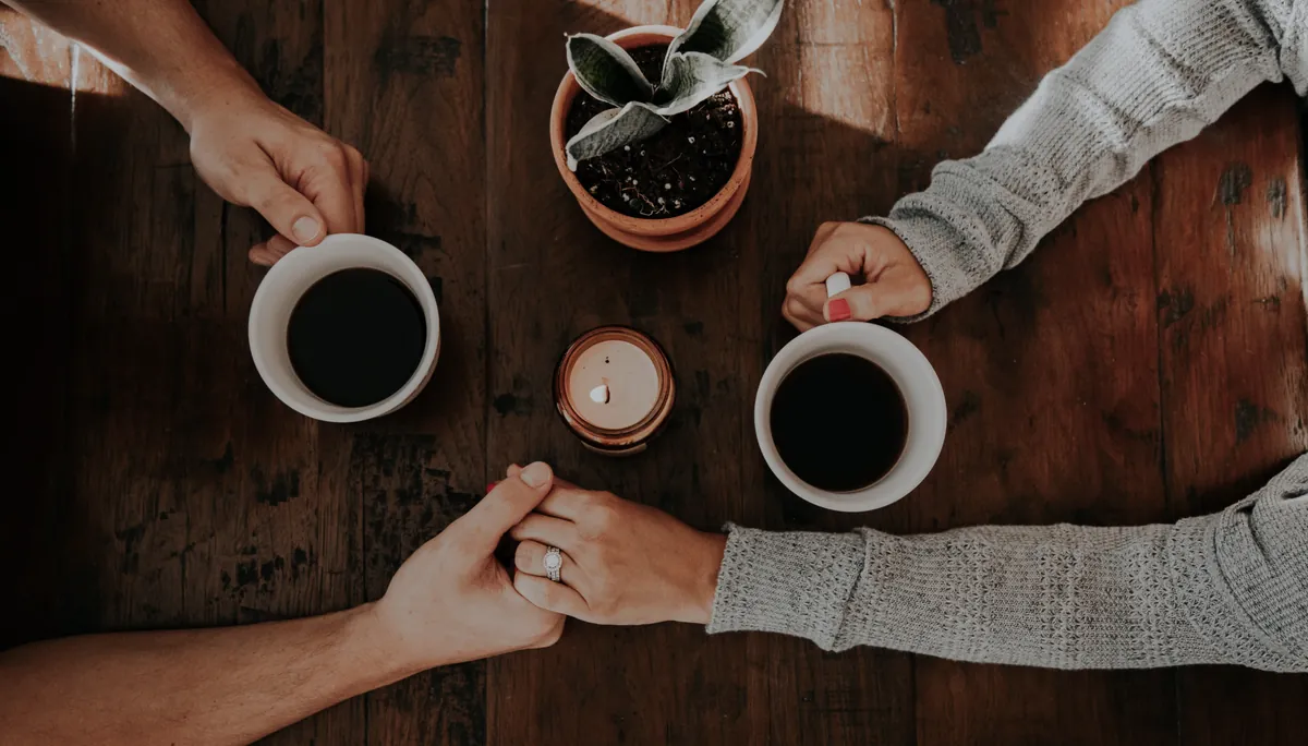 Deux personnes se tiennent la main autour de tasses de café